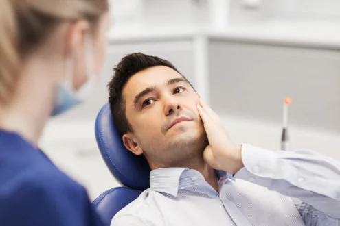 Man expressing pain holding his jaw.